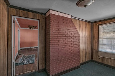 Hallway with wooden walls, ornamental molding, a textured ceiling, and brick wall