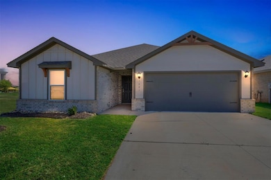 Ranch-style house featuring brick siding, a garage, board and batten siding, concrete driveway, and a front yard