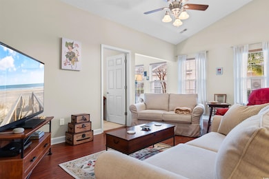 Living room featuring dark wood-type flooring, ceiling fan, and vaulted ceiling