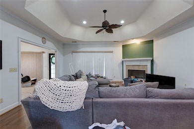 Living area with a ceiling fan, a fireplace, dark wood-style floors, crown molding, and recessed lighting