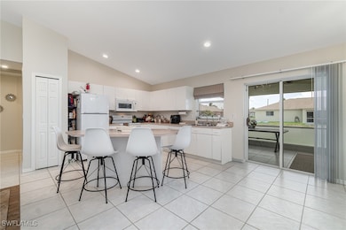 Kitchen featuring white appliances, a breakfast ba