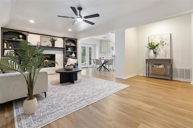 Living room featuring light wood-style flooring, a fireplace, crown molding, recessed lighting, and ceiling fan