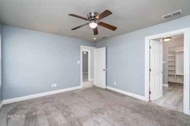Unfurnished bedroom featuring a spacious closet, a closet, ceiling fan, and light colored carpet