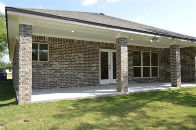 Back of house with brick siding, a patio, a lawn,