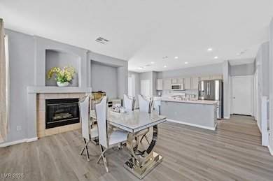 Dining space with a fireplace, light wood-type flooring, and recessed lighting