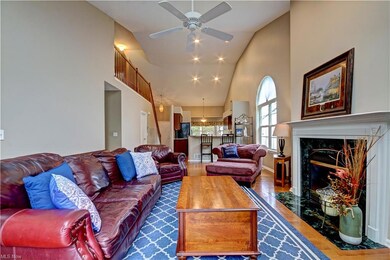 Hardwood floored living room featuring a high ceiling, a fireplace, lofted ceiling, and ceiling fan