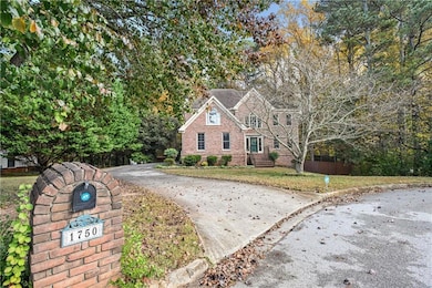 Traditional home with driveway, view of wooded area, and brick siding