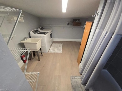 Laundry room with wood finished floors, independent washer and dryer, a sink, and baseboards