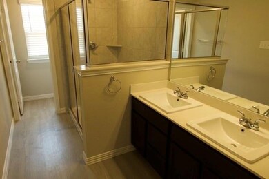 Bathroom with wood-type flooring, an enclosed shower, and double vanity