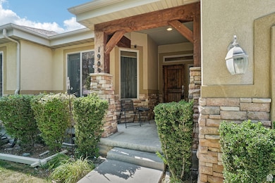 Entrance to property featuring stucco siding, stone siding, and covered porch