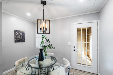 Dining space with a chandelier, ornamental molding, and wood finished floors