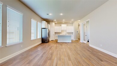 Open living, dining and kitchen with wood-look tile flooring.