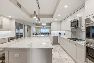 Kitchen with tasteful backsplash, light stone countertops, pendant lighting, stainless steel appliances, and a kitchen island