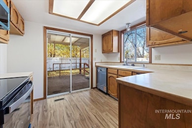 Kitchen with light countertops, brown cabinets, light wood-style flooring, appliances with stainless steel finishes, and plenty of natural light