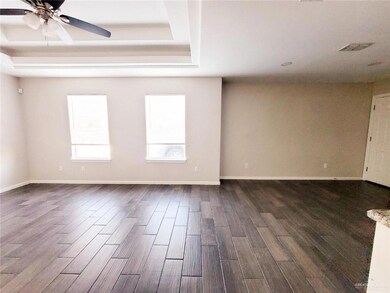 Spare room with dark wood-type flooring, a tray ceiling, and a ceiling fan