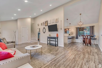 Living area featuring high vaulted ceiling, light wood-style floors, stairs, and recessed lighting