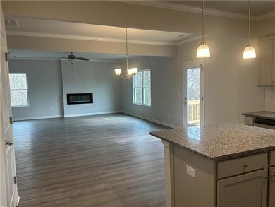 Kitchen featuring dark wood finished floors, crown molding, visible vents, a glass covered fireplace, and open floor plan