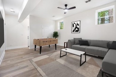 Living area featuring a ceiling fan, baseboards, visible vents, and light wood finished floors