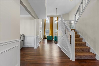 Stairway with wood finished floors, a wainscoted wall, and a decorative wall