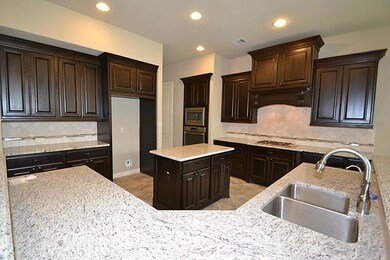 Kitchen offering tile floors, tumbled marble back splash, granite counter tops, gas range, built-in microwave and oven, island workspace and a breakfast bar opening to the breakfast room.