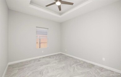 Unfurnished room with a raised ceiling, baseboards, and a ceiling fan