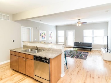 Kitchen featuring dishwasher, brown cabinetry, light wood-style flooring, ornamental molding, and open floor plan