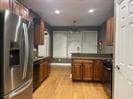 Kitchen with brown cabinetry, range, light wood-style floors, stainless steel refrigerator with ice dispenser, and recessed lighting