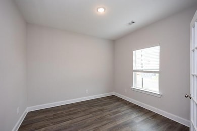 Unfurnished room with dark wood-type flooring, visible vents, and baseboards