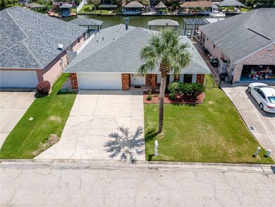 Aerial view of house with palm tree in front yard and extra large driveway.