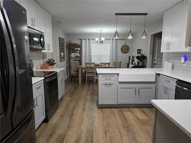 Kitchen with black appliances, a sink, a chandelie