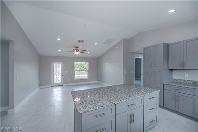 Kitchen with a center island, ceiling fan, vaulted