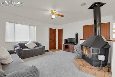 Living room and front entry with new paint, ceiling fan, wood stove, and new carpet