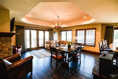 Dining room with a tray ceiling, dark wood-type flooring, french doors, recessed lighting, and a chandelier