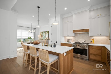 Kitchen with backsplash, brown cabinetry, stainless steel range, dark wood finished floors, and recessed lighting