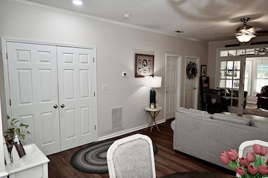 Living area with wood finished floors, crown molding, and a ceiling fan