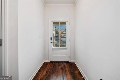 Doorway to outside featuring dark wood-type flooring, baseboards, and crown molding