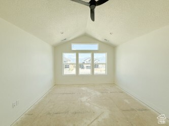 Unfurnished room with a textured ceiling and vaulted ceiling