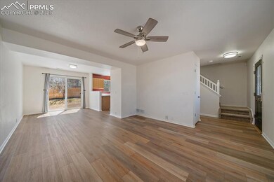 Unfurnished living room with a ceiling fan, visible vents, stairway, wood finished floors, and baseboards