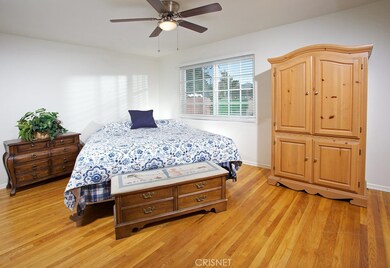 The generously sized primary suite is enriched by a sparkling picture window, lighted ceiling fan, ample closet space and striking original Oak hardwood floors; plus, a private en suite bathroom with vanity, large dressing mirror, mirrored medicine c