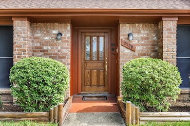 Inviting front entrance with charming brick accents and lush greenery.