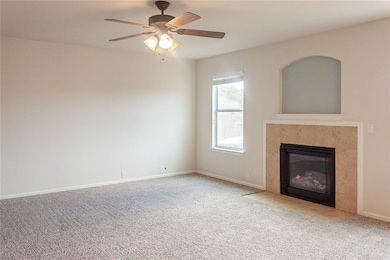 Unfurnished living room featuring carpet, a fireplace, and a ceiling fan