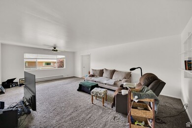 Living area featuring carpet, baseboard heating, and ceiling fan
