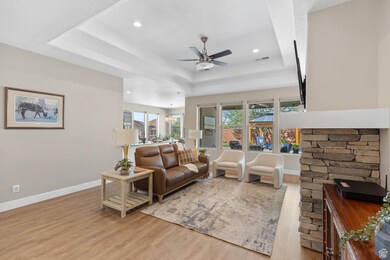 Living area with a tray ceiling, light wood finished floors, recessed lighting, and a ceiling fan