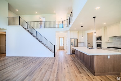 Kitchen with recessed lighting, tasteful backsplash, stainless steel appliances, light wood-type flooring, and white cabinets