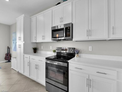 Kitchen featuring stainless steel appliances, light countertops, white cabinets, and light tile patterned flooring