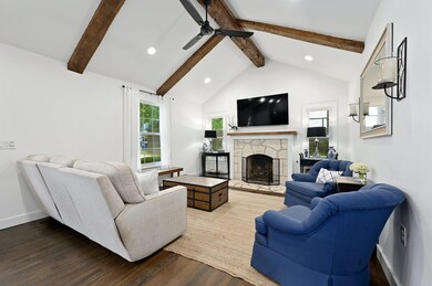 Living room with beam ceiling, a ceiling fan, woo