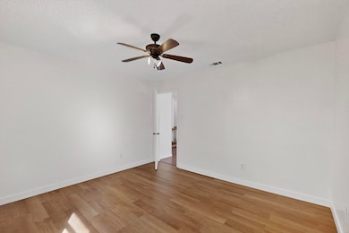 Empty room with light wood finished floors, a ceiling fan, and a textured ceiling