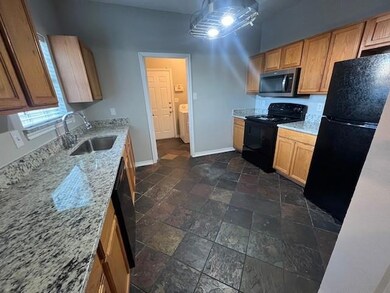Kitchen featuring black appliances, light stone co
