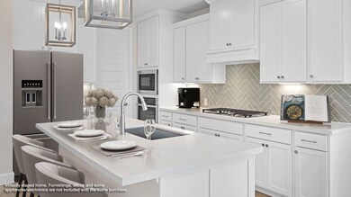 Kitchen with hanging light fixtures, a breakfast bar, decorative backsplash, a center island with sink, and white cabinetry