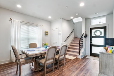 Dining room with dark wood-style floors, stairs, and recessed lighting
